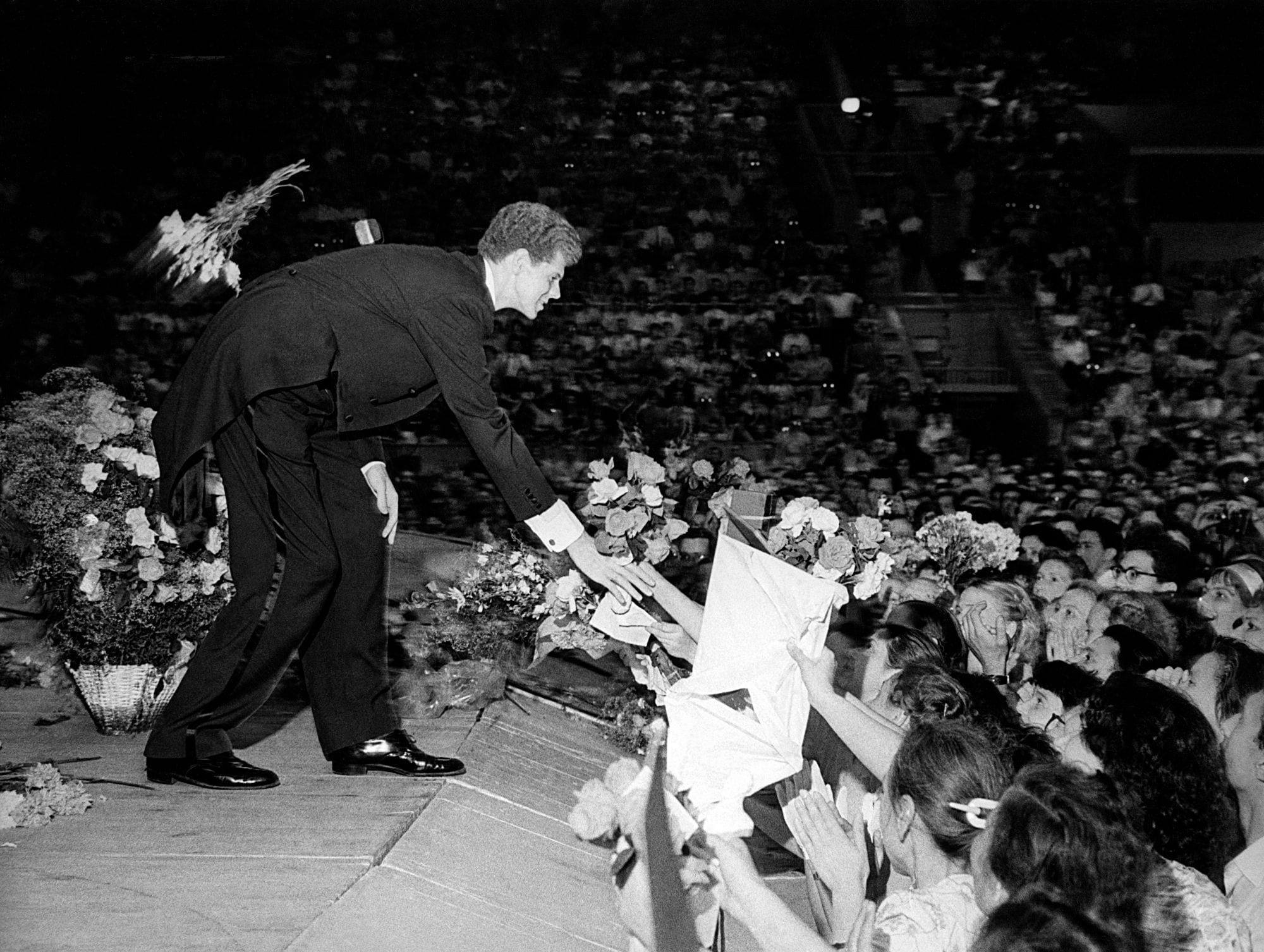 Van Cliburn reaching down from the stage to shake hands with admirers